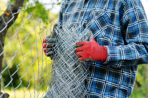 A man wearing red gloves installing a fence.