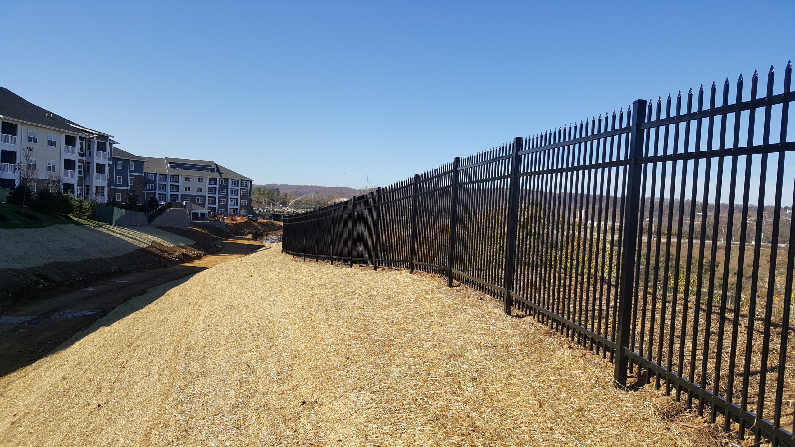 A fence on a hill near an apartment complex.